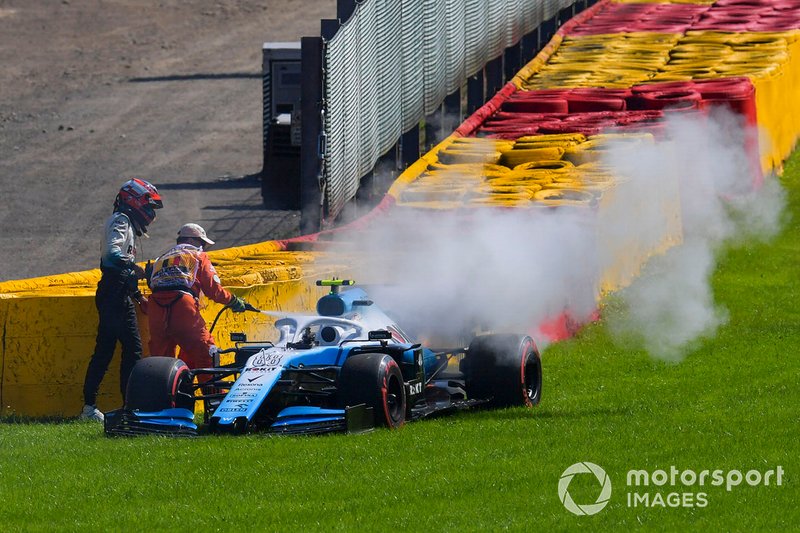 Robert Kubica, Williams Racing FW42, helps a marshal extinguish the fire