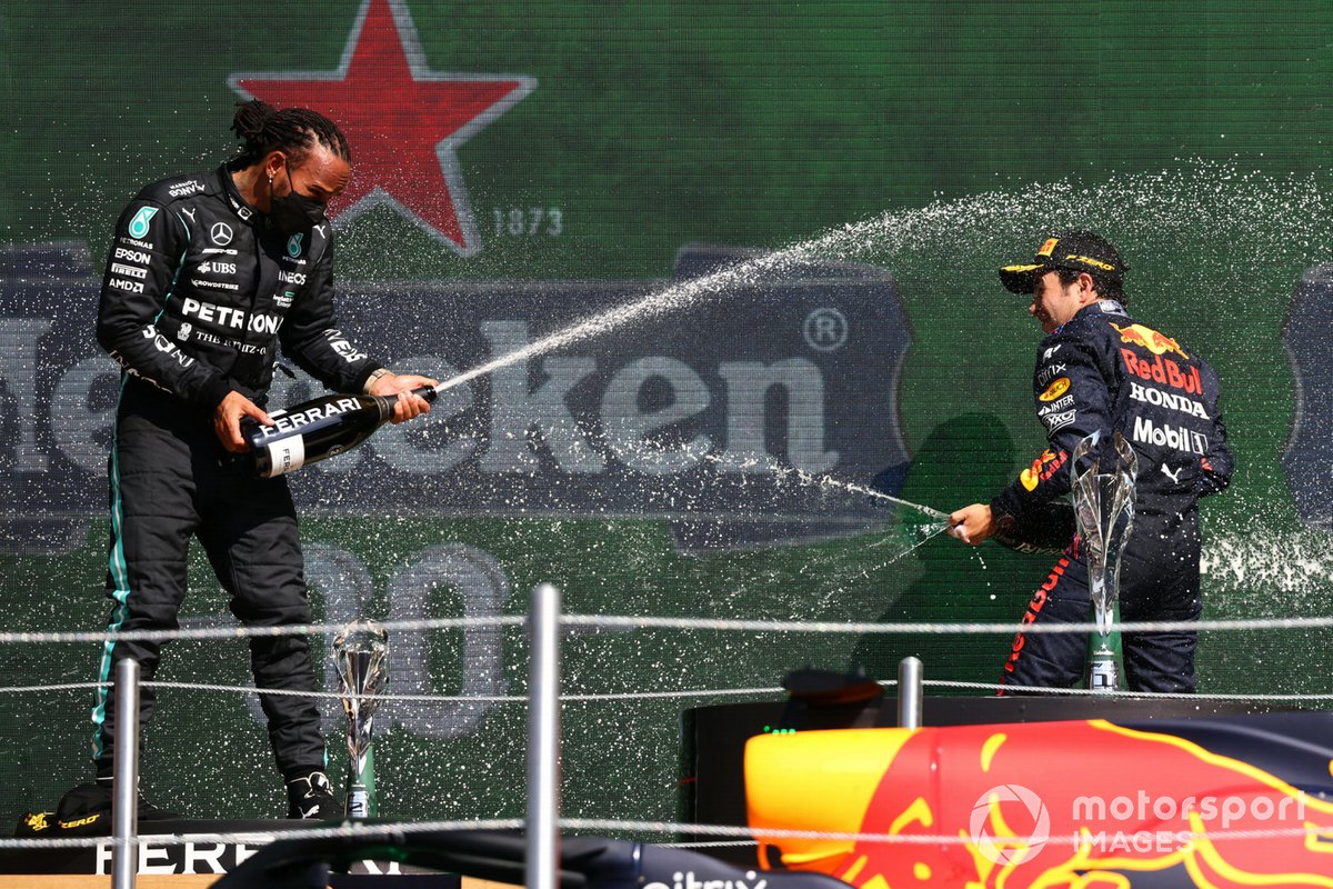 Lewis Hamilton, Mercedes, 2nd position, and Sergio Perez, Red Bull Racing, 3rd position, spray Champagne on the podium
