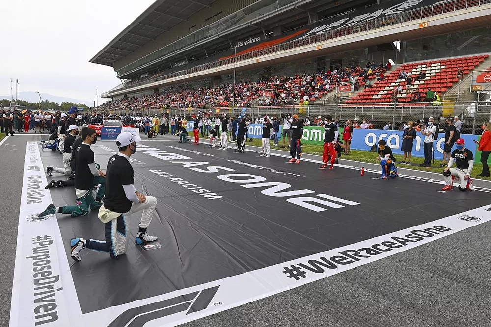The drivers stand and kneel on the grid in support of the We race as one campaign