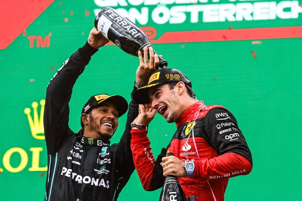 Le troisi&egrave;me Lewis Hamilton, Mercedes-AMG, verse du Champagne sur le vainqueur Charles Leclerc, Ferrari, sur le podium