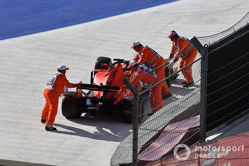 Los marshals mueven el coche de Sebastian Vettel, Ferrari SF90, fuera del circuito