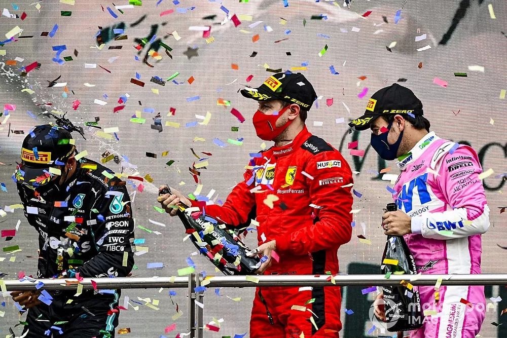 Sebastian Vettel, Ferrari, 3rd position, and Sergio Perez, Racing Point, 2nd position, spray Lewis Hamilton, Mercedes-AMG F1, 1st position, with Champagne on the podium
