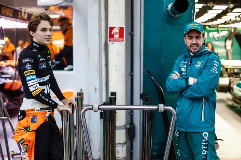 Oscar Piastri, McLaren F1 Team, y Fernando Alonso, Aston Martin F1 Team, hablan en el pitlane