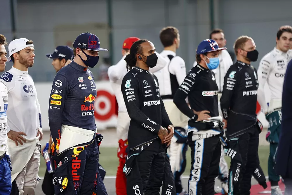 Max Verstappen, Red Bull Racing, Lewis Hamilton, Mercedes, Fernando Alonso, Alpine F1, and the other drivers stand on the grid for the national anthem prior to the start