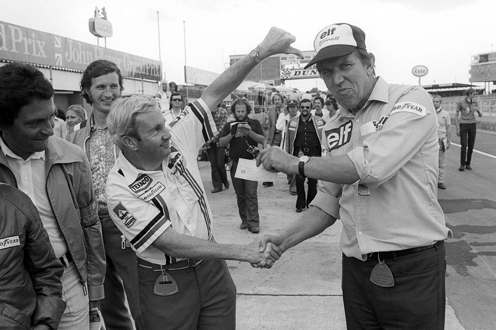 Teddy Mayer, propietario del equipo McLaren entrega un cheque a Ken Tyrrell, propietario del equipo Tyrrell después de perder una competencia de cambio de neumáticos en los pits
