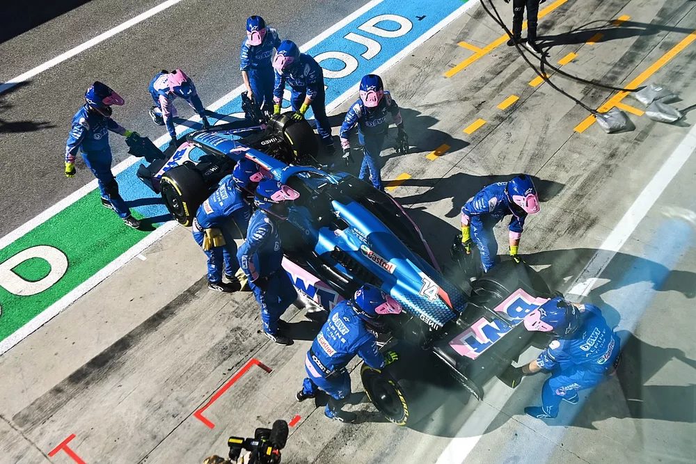Los mec&aacute;nicos de Alpine empujan el coche retirado de Fernando Alonso, el Alpine A522, hacia el garaje