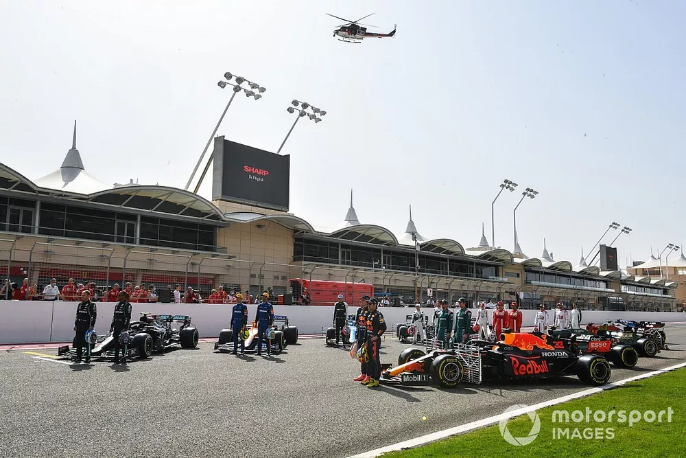 The drivers stand in front of their cars on the grid