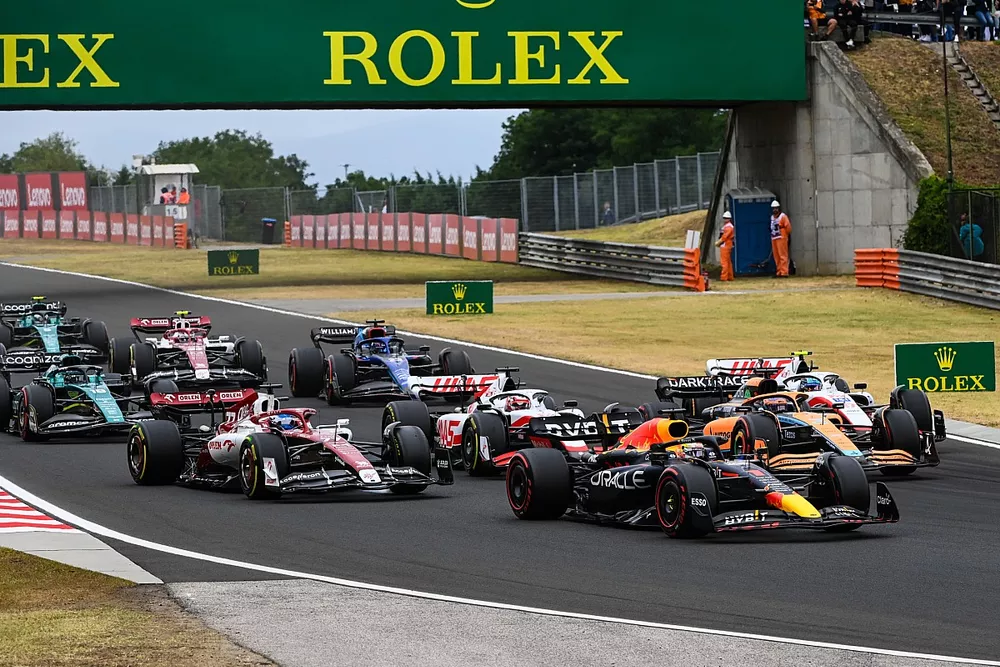 Max Verstappen, Red Bull Racing RB18, Daniel Ricciardo, McLaren MCL36, Mick Schumacher, Haas VF-22, Kevin Magnussen, Haas VF-22, Valtteri Bottas, Alfa Romeo C42, the remainder of the field on the opening lap