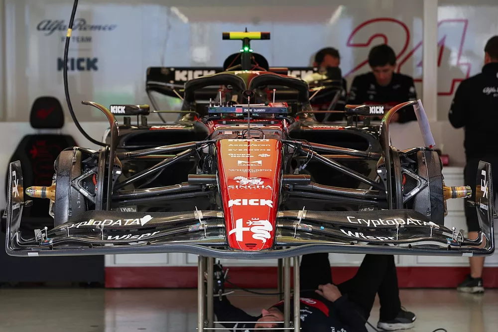 A mechanic works under the car of Zhou Guanyu, Alfa Romeo C43 