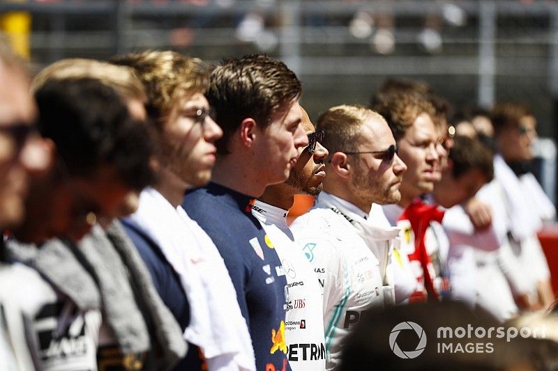 Los pilotos se alinean con los ni&ntilde;os de la cuadr&iacute;cula para el himno nacional antes de la salida.