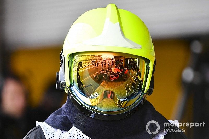 El coche de Alex Albon, Red Bull RB15, visto en el reflejo de una visera de los bomberos