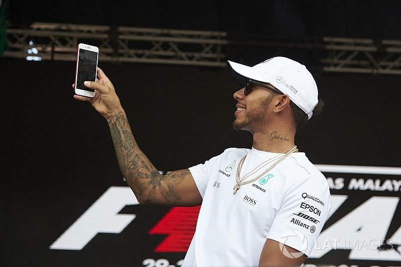 Lewis Hamilton, Mercedes AMG F1, uses his phone on stage
