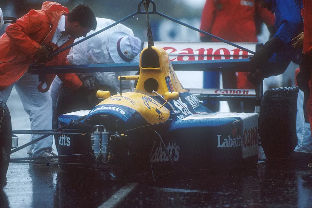 Oficiales de pista retiran el chasis de Williams FW14 Renault de Nigel Mansell fuera de la pista des