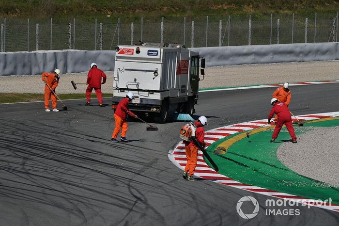 Marshals clear gravel from the track