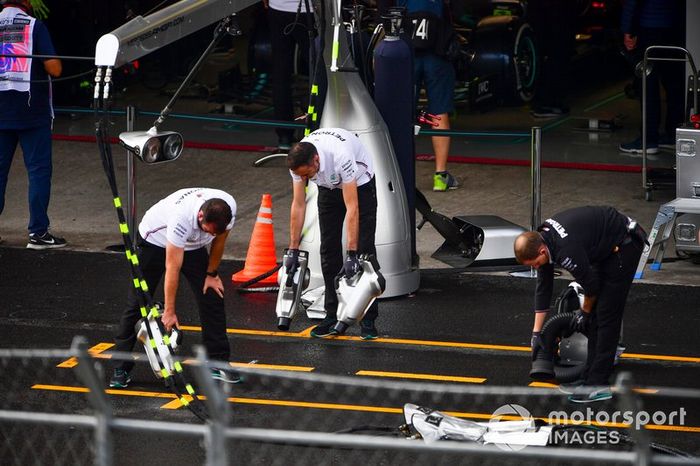 Los mecánicos de Mercedes intentan secar el asfalto fuera de su garaje