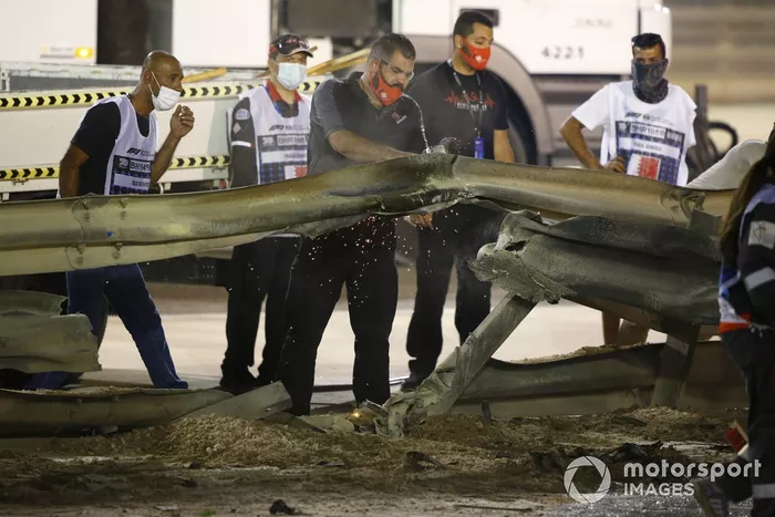 Los oficiales retiran los restos después del choque de Romain Grosjean, Haas VF-20, en la primera vuelta