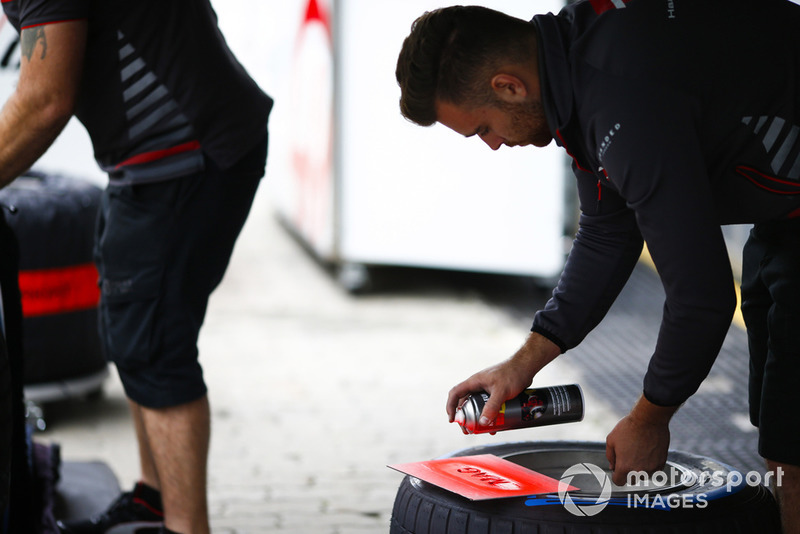 A Haas team member sprays paints a marking onto one of Kevin Magnussen's tyres