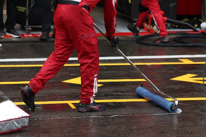 Un mecánico de Ferrari seca la zona de boxes fuera del garaje del equipo después de que una bandera roja debido a la visibilidad retrasara el inicio del Gran Premio de Bélgica de Fórmula Uno en el circuito de Spa-Francorchamps en Spa, el 27 de julio de 20