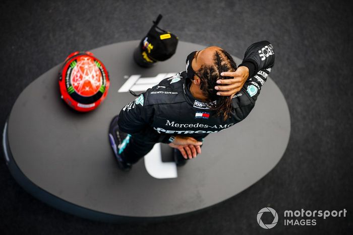 Lewis Hamilton, Mercedes-AMG F1, 1ª posición, en el podio con su trofeo y el casco de Michael Schumacher