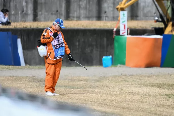 Un jefe de pista riega la hierba seca a lo largo de la pista