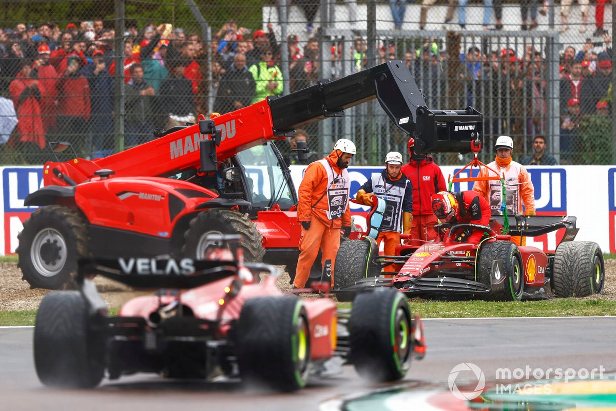 Charles Leclerc, Ferrari F1-75, passes as Marshals assist Carlos Sainz Jr., Ferrari F1-75, in the gravel