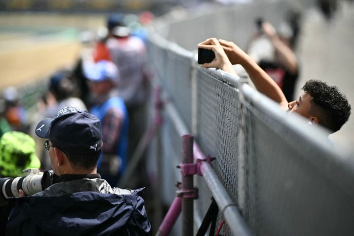 Un espectador intenta filmar la competición desde encima de la valla durante la tercera sesión de entrenamientos.
