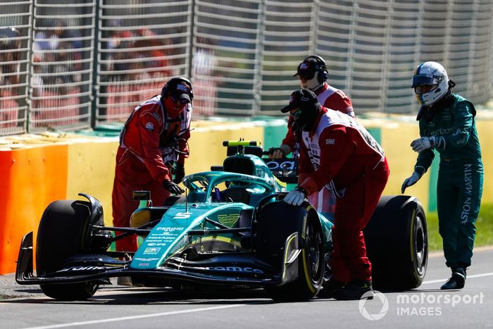 Oficiales de pista asisten a Sebastian Vettel, Aston Martin AMR22, tras abandonar en la FP1