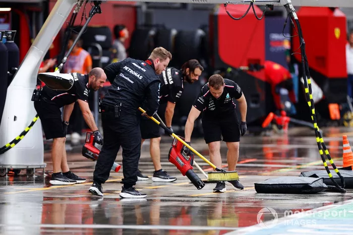 Los mecánicos de Mercedes barren el agua del pit lane