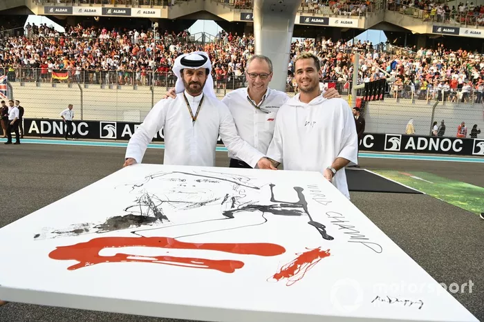 Mohammed bin Sulayem, presidente de la FIA, Stefano Domenicali, director general de la Fórmula 1, el artista Sr. Dripping presentan un retrato de Sebastian Vettel, Aston Martin, en la parrilla de salida