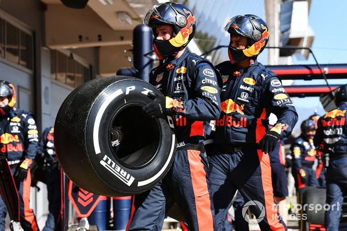 Red Bull mechanics carry a tyre after a pit stop