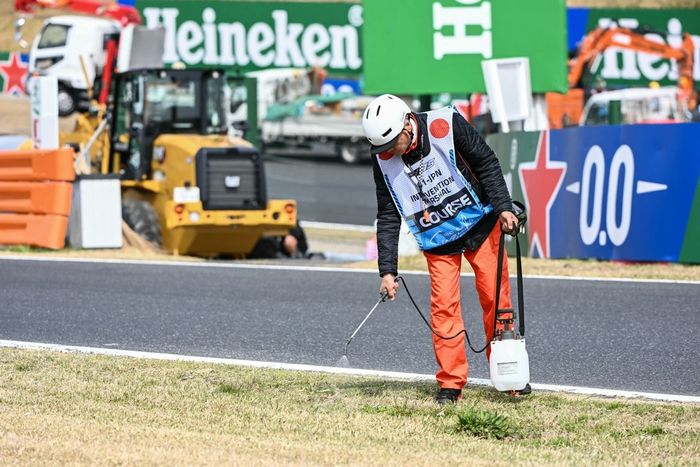 Un jefe de pista riega la hierba seca a lo largo de la pista