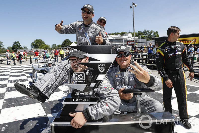 Des membres de l'équipe de Josef Newgarden, Team Penske Chevrolet, reviennent au camion avec le trophée