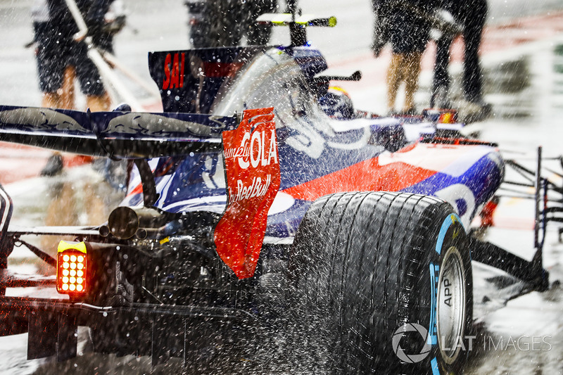 Water sprays from the rears of Carlos Sainz Jr., Scuderia Toro Rosso STR12, in the pit lane