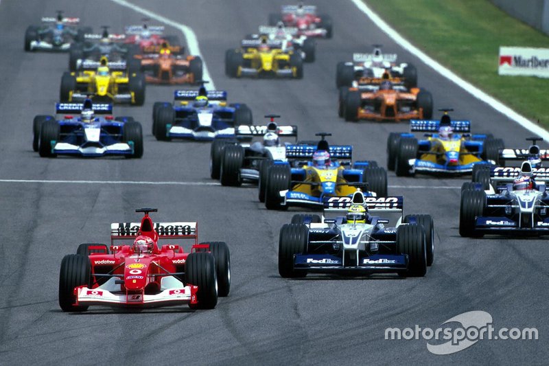 El inicio de la carrera y Michael Schumacher, Ferrari, lidera a Ralf Schumacher, Williams BMW FW24, Juan Pablo Montoya, Williams BMW FW24.