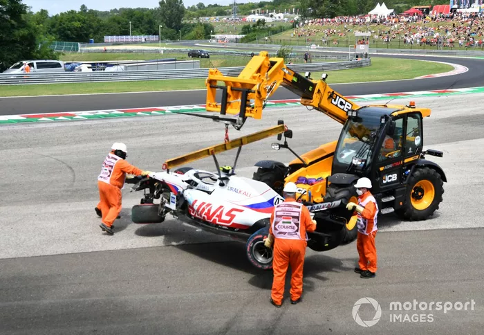 Los oficiales retiran el coche dañado de Mick Schumacher, Haas VF-21, de una barrera de neumáticos tras su accidente en la FP3