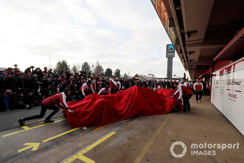 Alfa Romeo Racing monteurs met de Alfa Romeo Racing C38 onder het doek