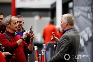 Un fan toma una foto de Johnny Herbert sosteniendo un llavero de un oso de peluche de Ferrari