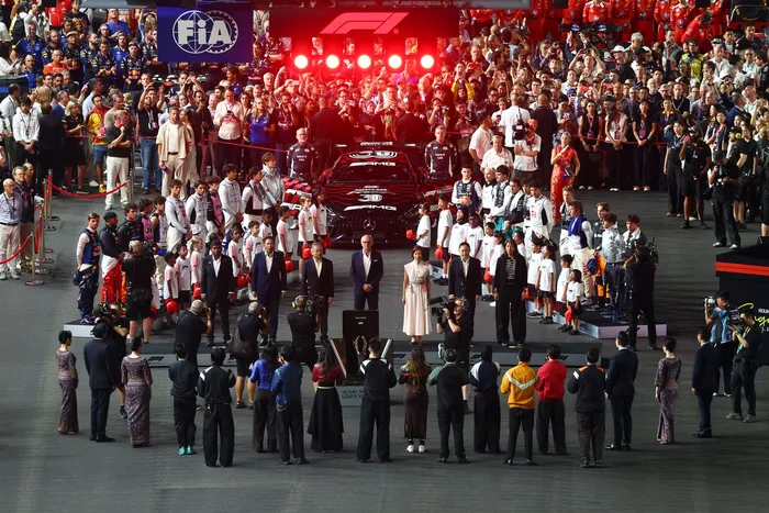     Drivers, official delegates, grid children line up on the grid