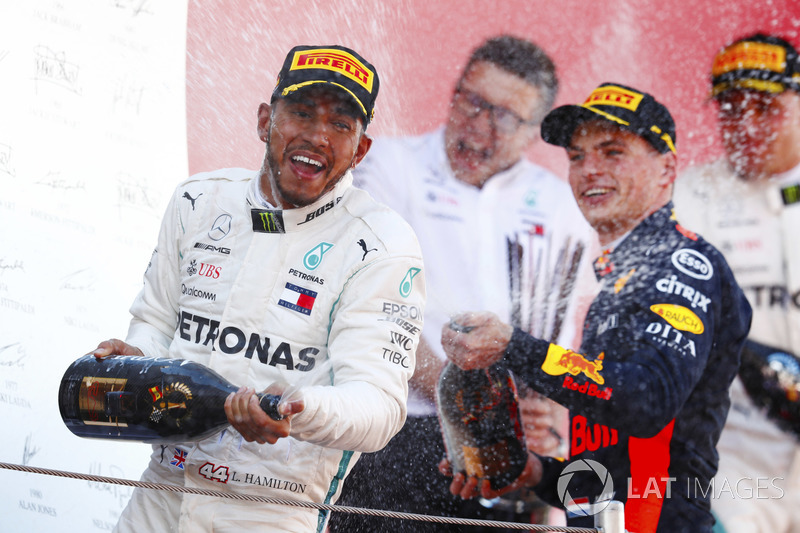 Lewis Hamilton, Mercedes AMG F1, and Max Verstappen, Red Bull Racing celebrate on the podium by spraying champagne