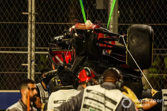 Los oficiales de pista retiran el coche dañado de Charles Leclerc, Ferrari SF21, del circuito