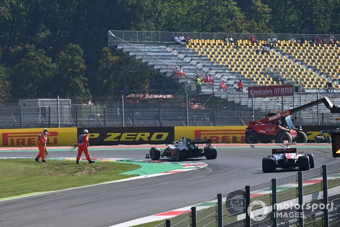 Los oficiales limpian la pista del monoplaza de Romain Grosjean, Haas VF-20, mientras pasa Kimi Raikkonen, Alfa Romeo Racing C39