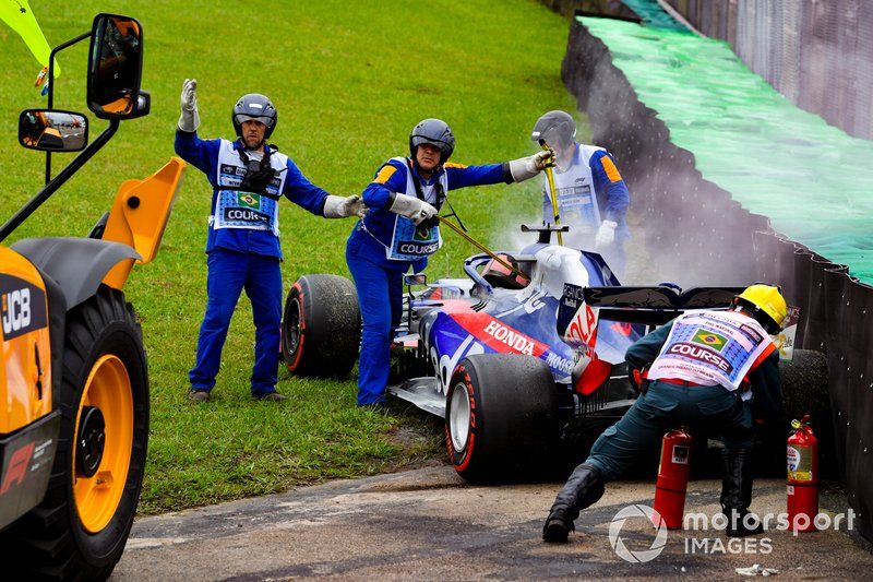 Los oficiales asisten al coche humeante de Daniil Kvyat, Toro Rosso STR14, con extintores de incendios