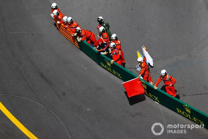 Los comisarios ondean las banderas rojas tras un accidente en la primera vuelta