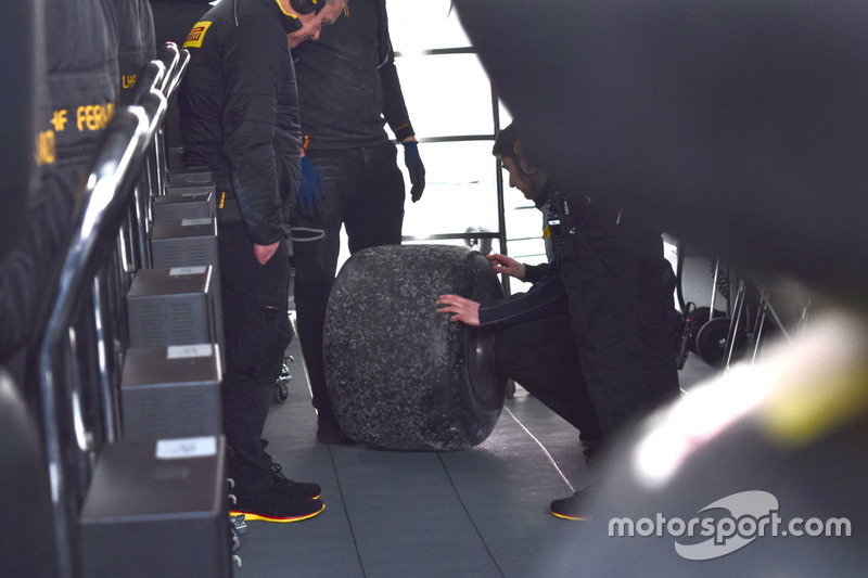 Kru Pirelli dan McLaren memeriksa ban kanan-belakang yang terlepas dari mobil Fernando Alonso