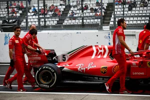 Los ingenieros de Ferrari mueven el auto de Sebastian Vettel, Ferrari SF71H, en el pit lane.