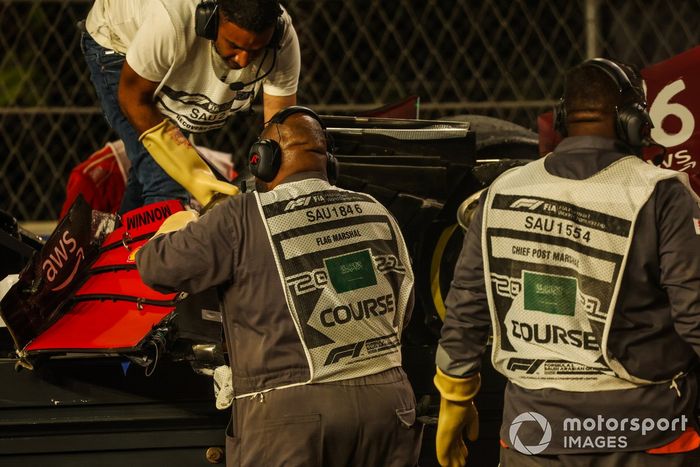 Un oficial de pista retira el alerón delantero del coche de Charles Leclerc, Ferrari SF21, del circuito