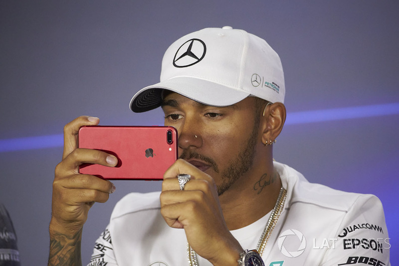 Lewis Hamilton, Mercedes AMG F1, uses his mobile phone in the press conference