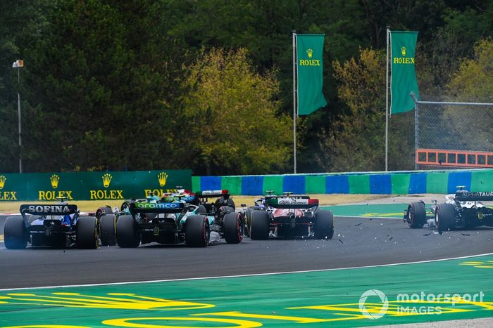 Una colisión hace volar escombros en la primera vuelta mientras Valtteri Bottas, Alfa Romeo C42, Lance Stroll, Aston Martin AMR22, Alex Albon, Williams FW44, Yuki Tsunoda, AlphaTauri AT03, Zhou Guanyu, Alfa Romeo C42, luchan por la posición