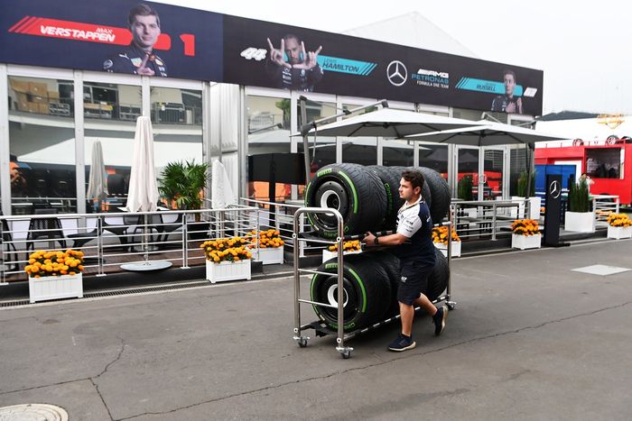 Un mecánico de la Scuderia AlphaTauri rueda neumáticos Pirelli por el paddock