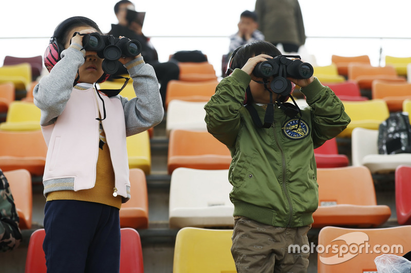 De jeunes fans regardent les F1 avec des jumelles